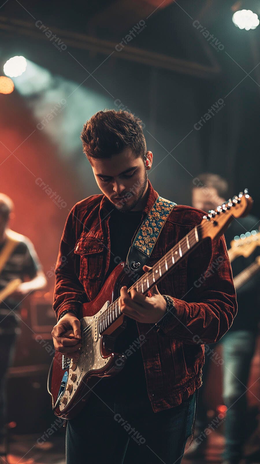 Jovem guitarrista masculino tocando guitarra elétrica vermelha no palco com luzes quentes