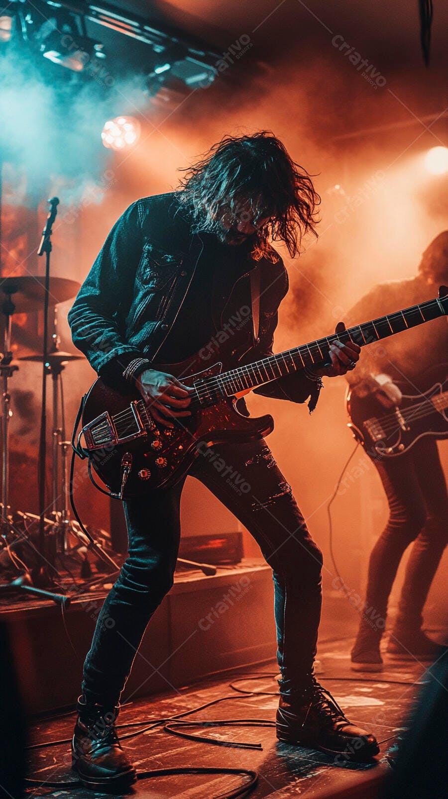 Guitarrista homem de cabelo comprido tocando guitarra elétrica em show com luzes laranja e azul neon