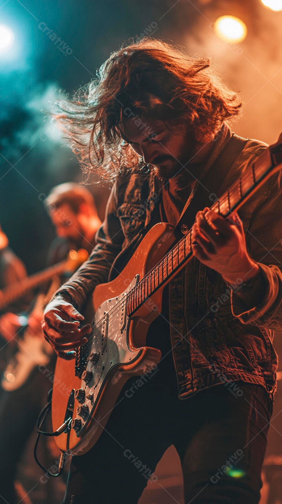 Guitarrista de cabelo comprido tocando guitarra elétrica em show com luzes laranja e azul