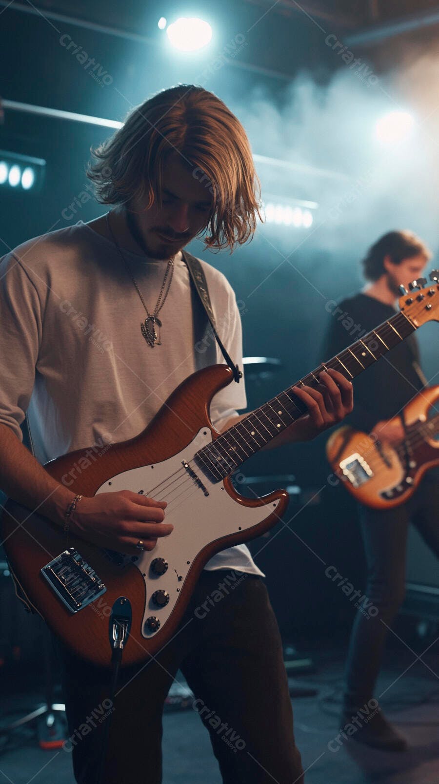 Homem guitarrista de cabelos loiros tocando guitarra elétrica em palco iluminado com fumaça