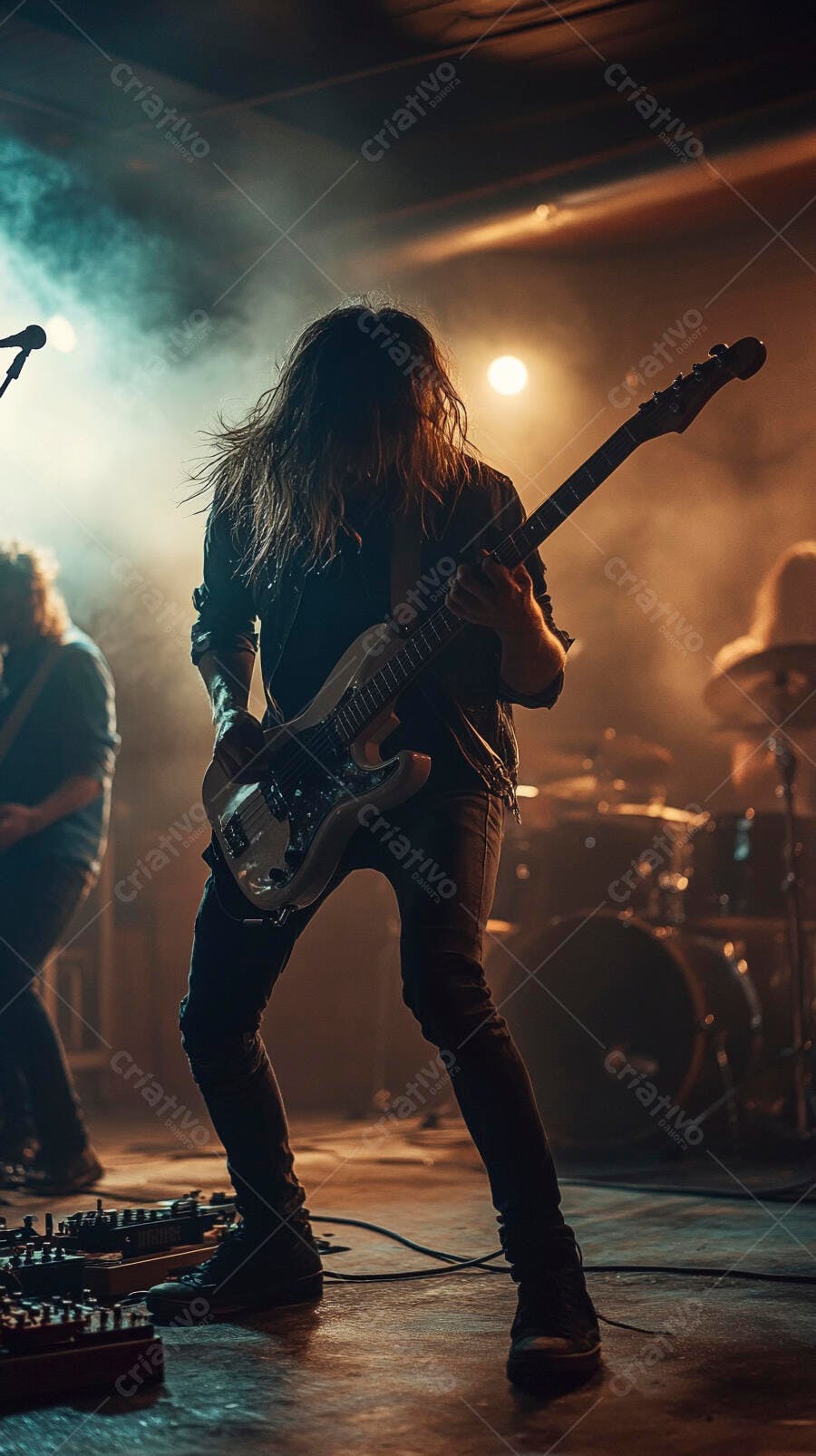 Baixista masculino com cabelo comprido tocando em show de rock com luzes âmbar