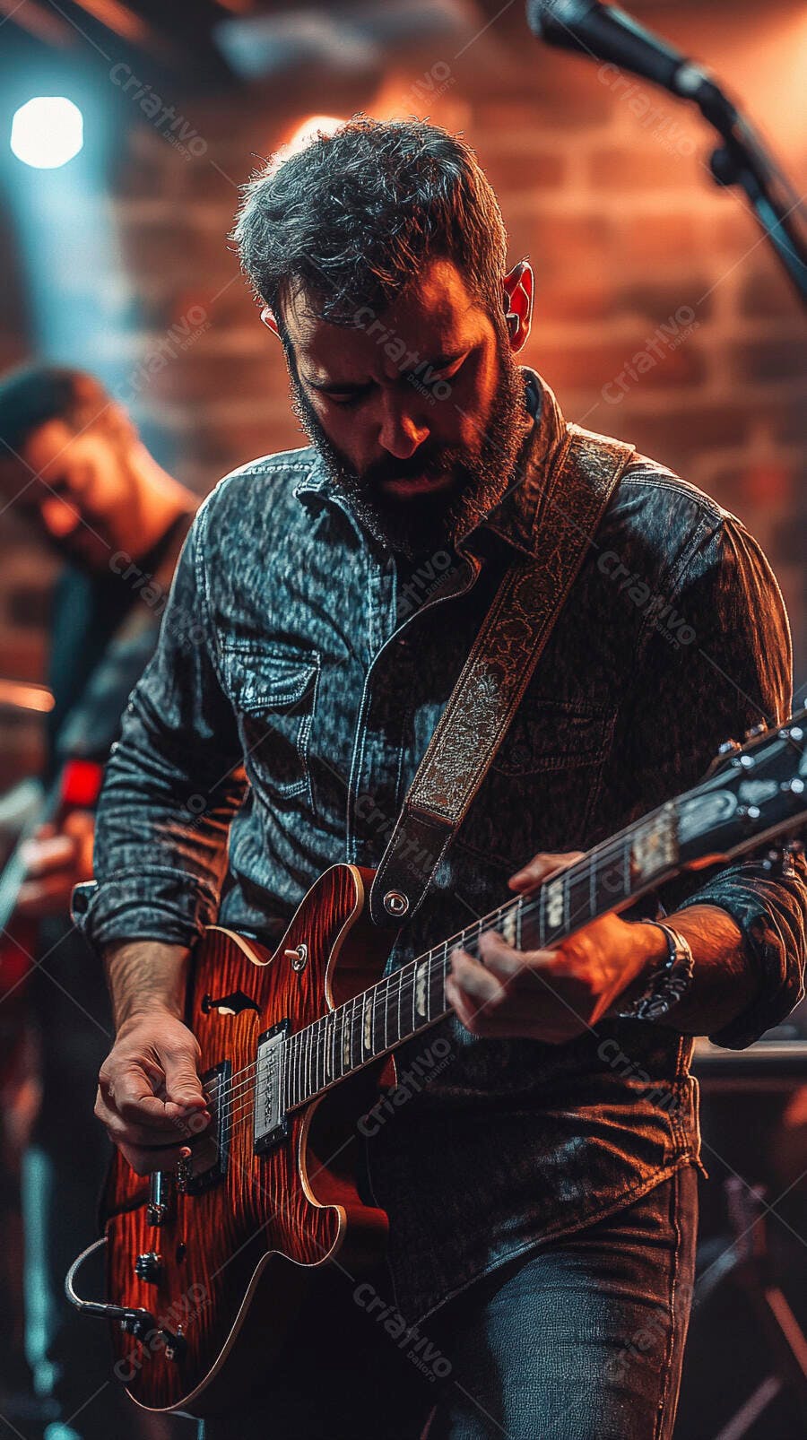 Homem guitarrista barbudo de camisa jeans tocando guitarra elétrica vermelha no palco