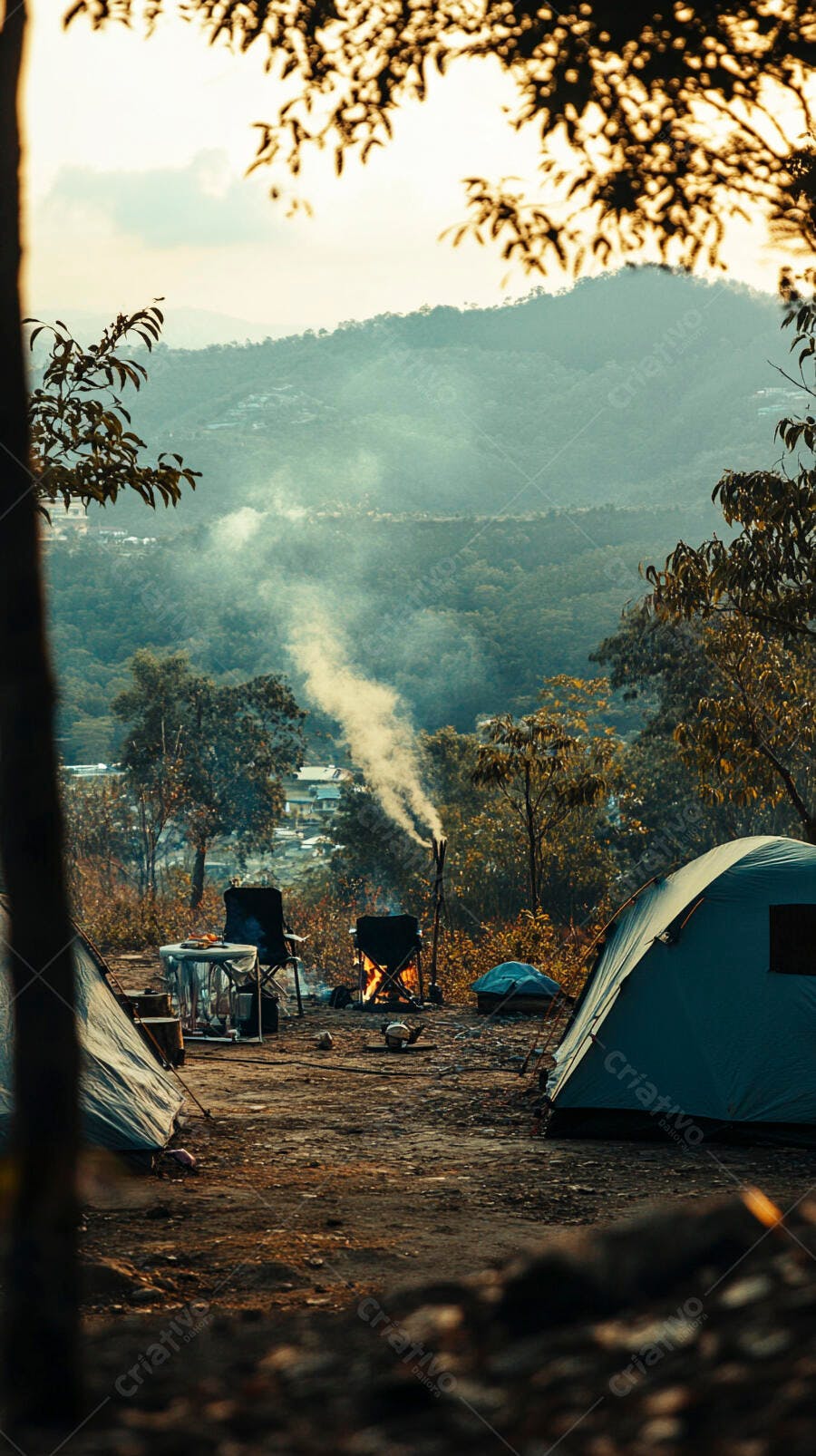Acampamento rústico com fogueira fumegante e tendas azuis entre montanhas